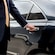 A professional driver in a suit opening the rear door of a luxury sedan